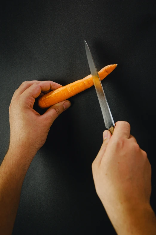 man holding a carrot and a knife through it