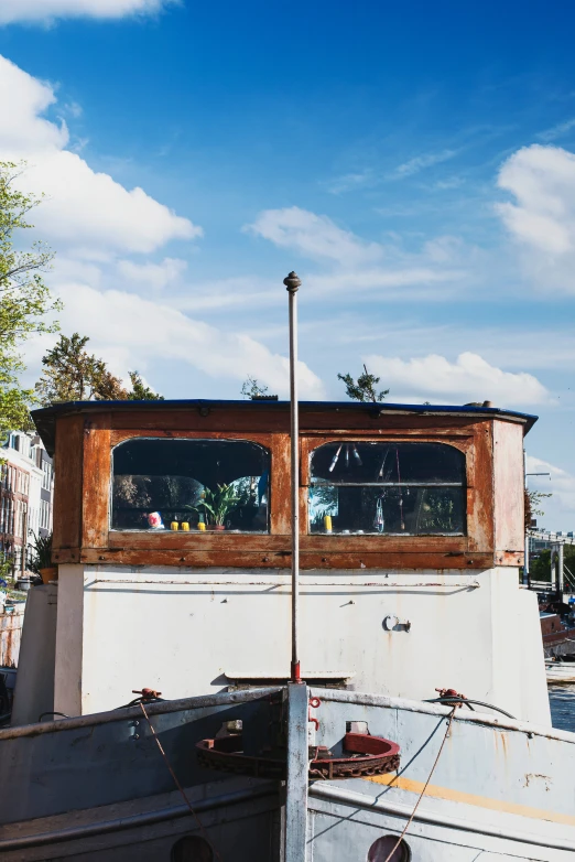 a boat with a window and wooden roof docked in the water