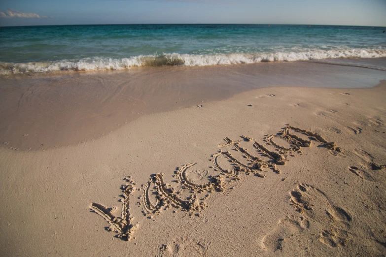 the word summer spelled out in sand on a beach