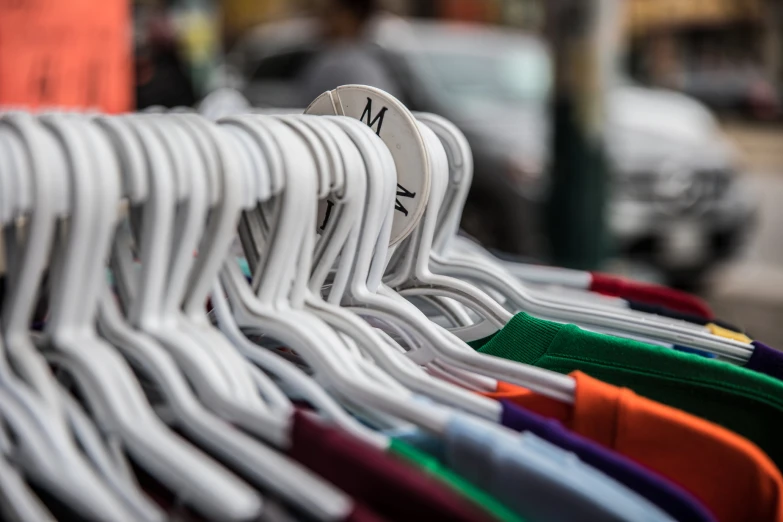 various colored t - shirts hanging on a display in a store