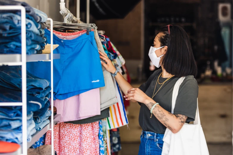 woman in white mask looking at clothing items