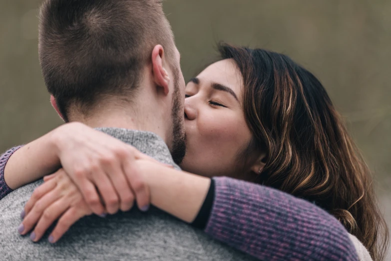 a woman kissing a man's forehead outside in the forest