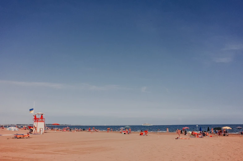 a beach area with people sitting on chairs and standing around