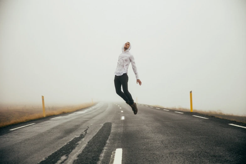 a man is jumping in the air on a foggy street