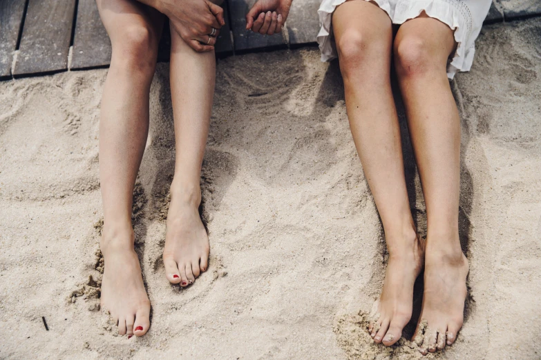 a man is holding a woman's legs on the beach