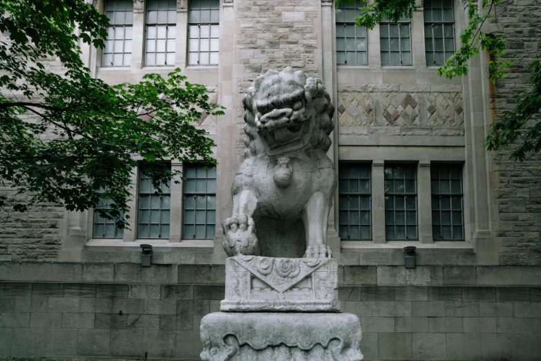 a statue of a lion is in the foreground and a building in the back ground