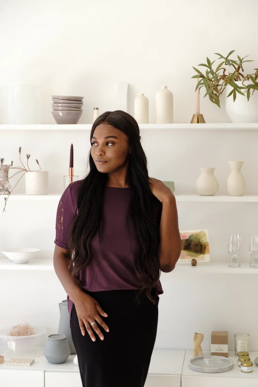 a black woman standing next to shelves of vases and flowers