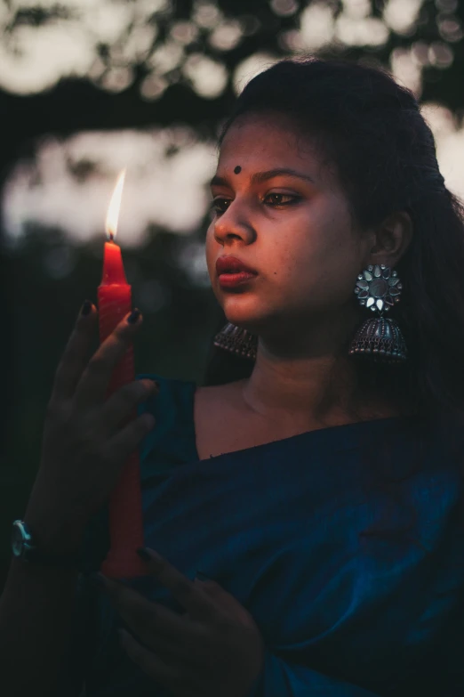a girl with earrings holding a candle lite