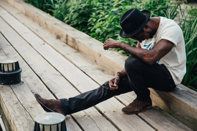 a man with his legs hanging out on a dock looking at his watch