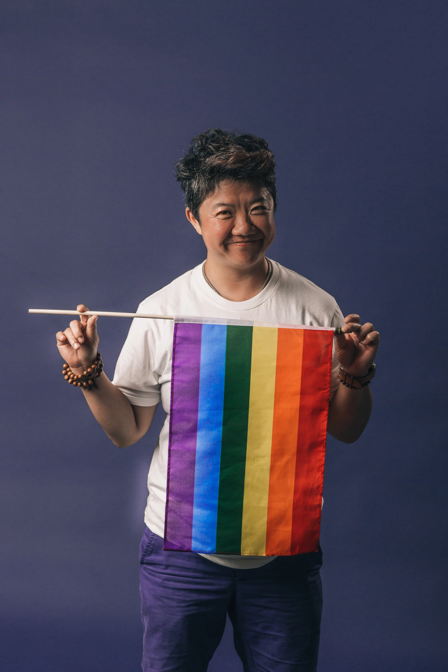 a man holding up a multicolored flag with white pins in it