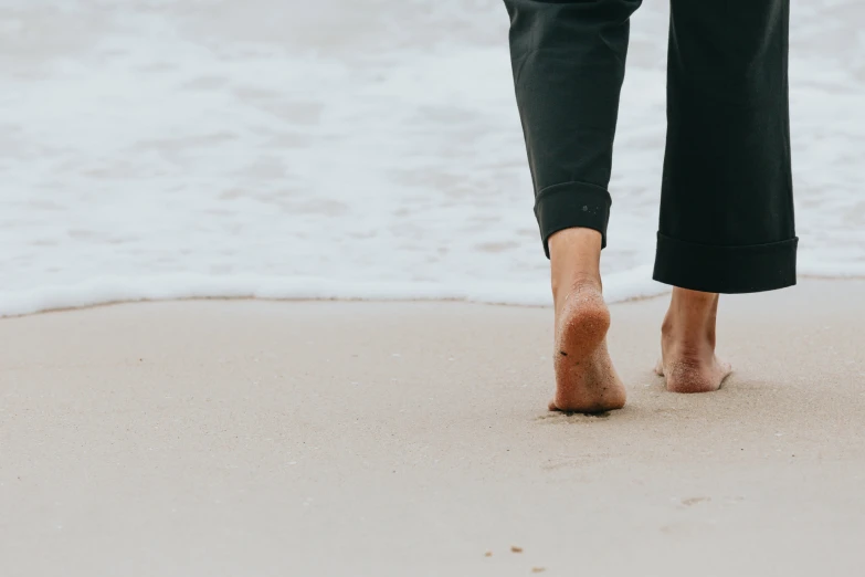 woman walking on sandy beach in her wet pants