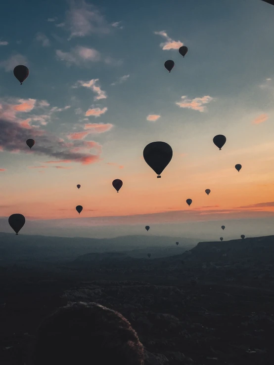 balloons floating in the sky at sunset over a mountain