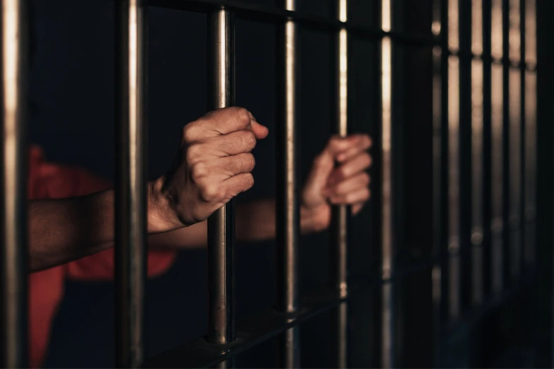 a man is holding onto bars of a  cell