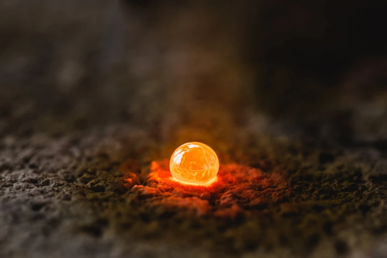 a glowing ball sits in a pile of brown dirt