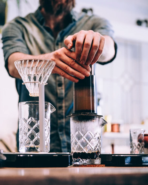 a close up of a person pouring a drink into glasses