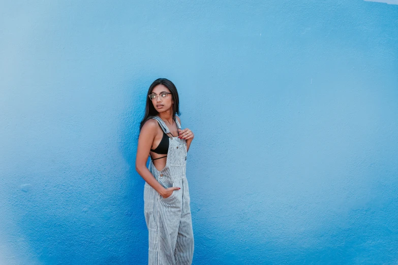 woman in a  dress posing against a blue wall