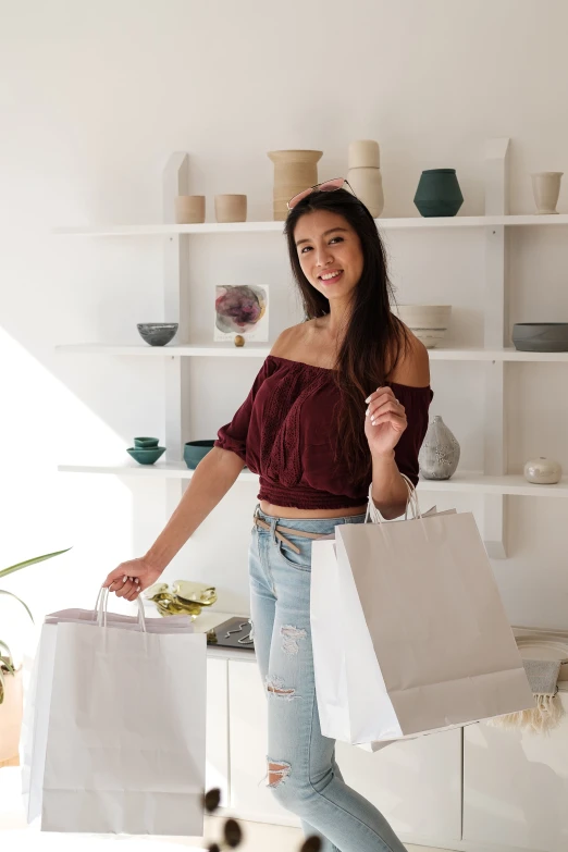 young woman holding three shopping bags and smiling