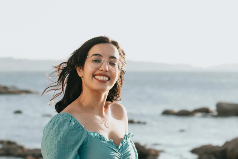 the woman smiles in front of a body of water