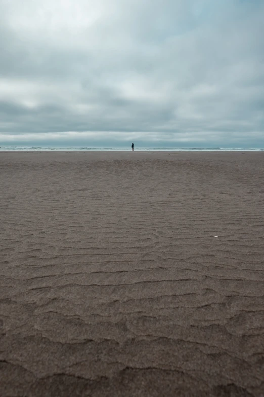 a person is walking in the sand at the beach