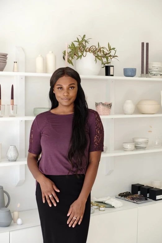 a woman standing next to shelves filled with pottery