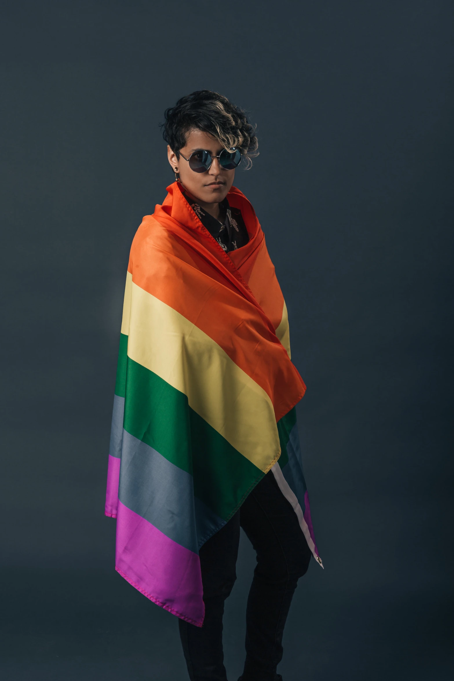 a woman standing with a large colored blanket on her back