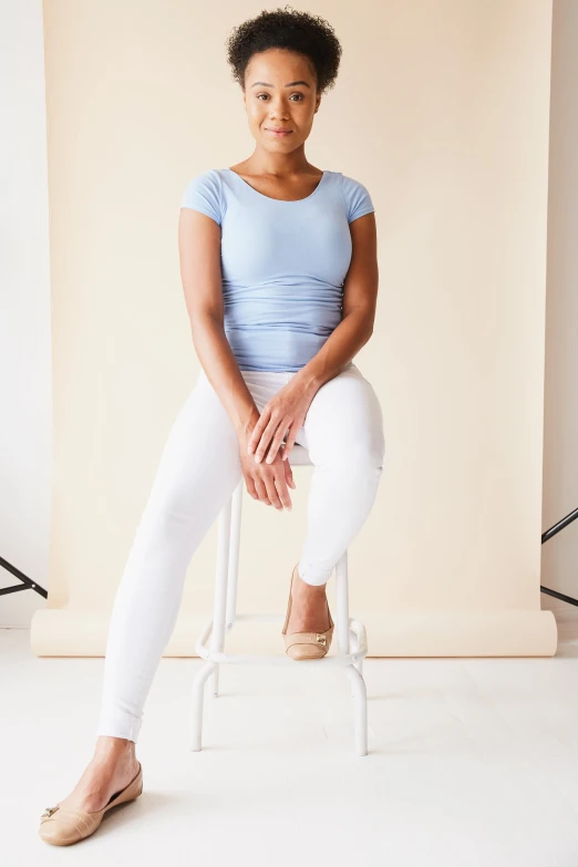 a girl sitting on a stool in a po studio