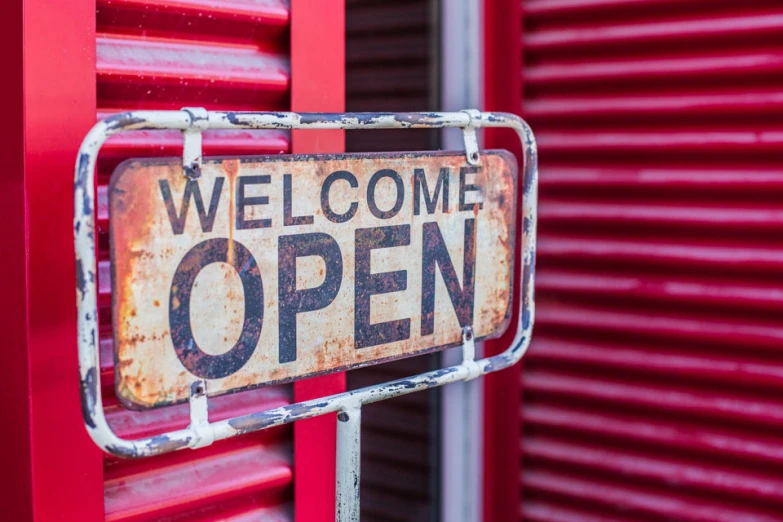 a red metal entrance with a welcome sign and words on it