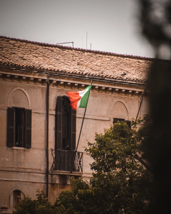 an orange and green flag waving from a balcony of a building