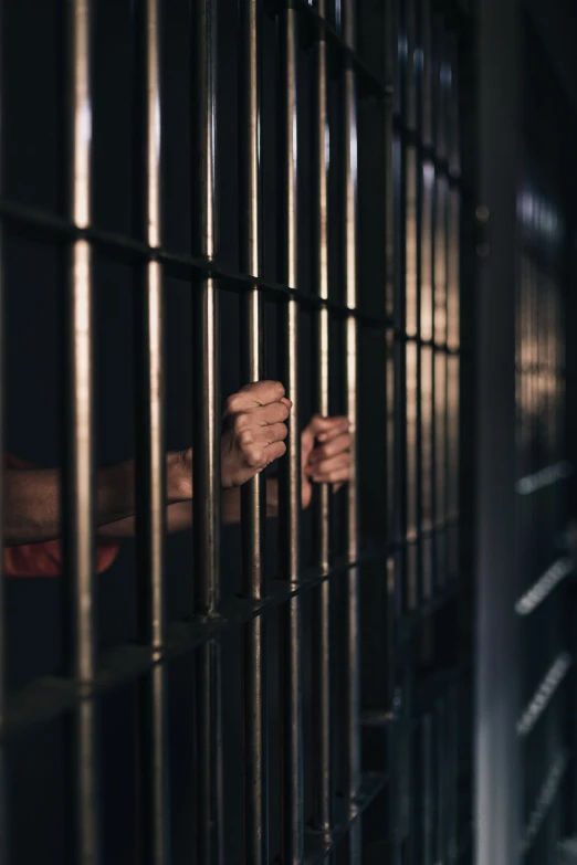 the person's hand is holding a bar on the top of the cage