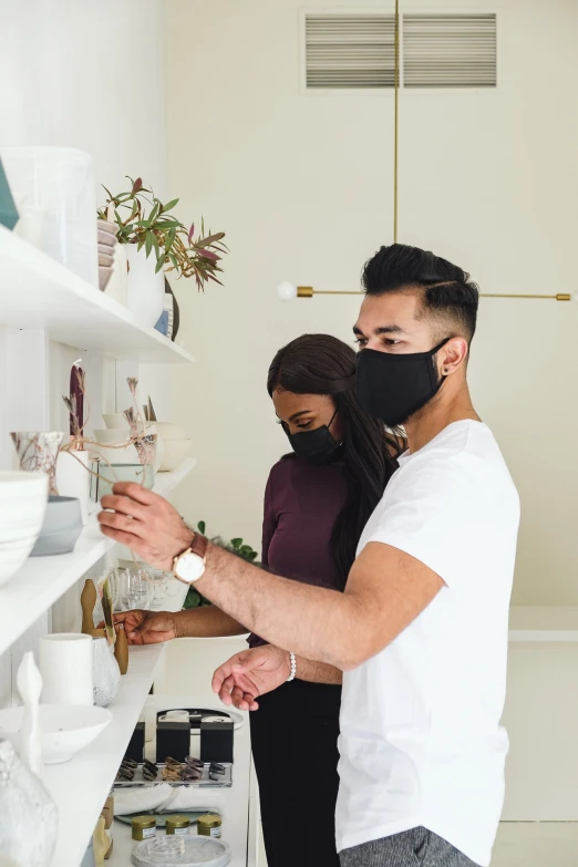 a man wearing a face mask and a woman behind a kitchen counter