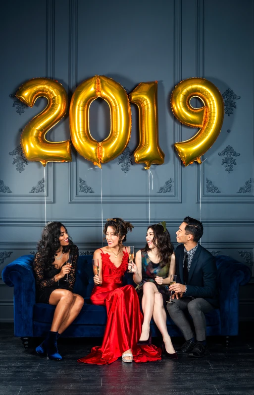 four young people sitting on a couch posing for an event