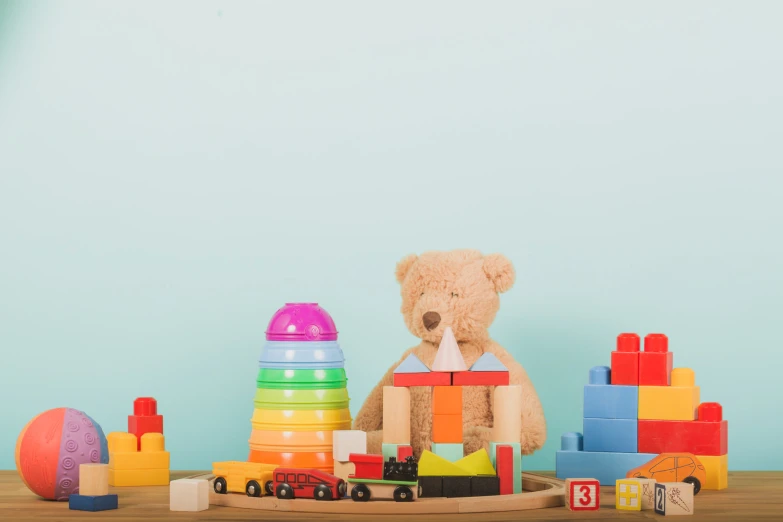 teddy bear holding wooden toy blocks near many toys