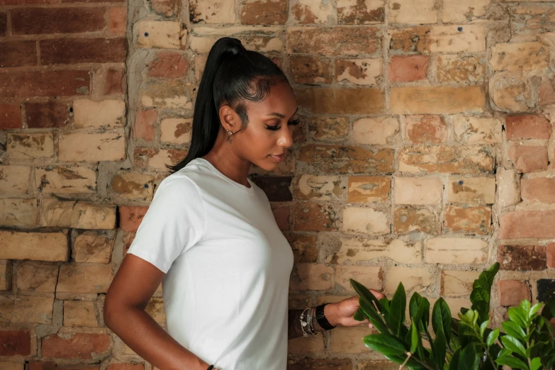 woman holding a leafy plant near brick wall