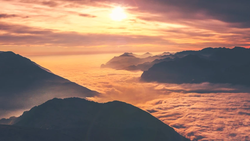 clouds cover the ground and a mountain below