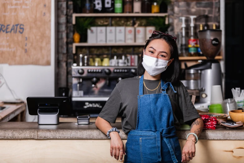 a woman wearing a face mask and holding a coffee pot