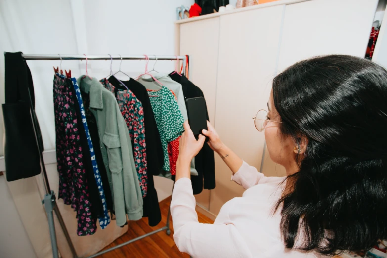 a woman looking at clothing hanging on clothes racks