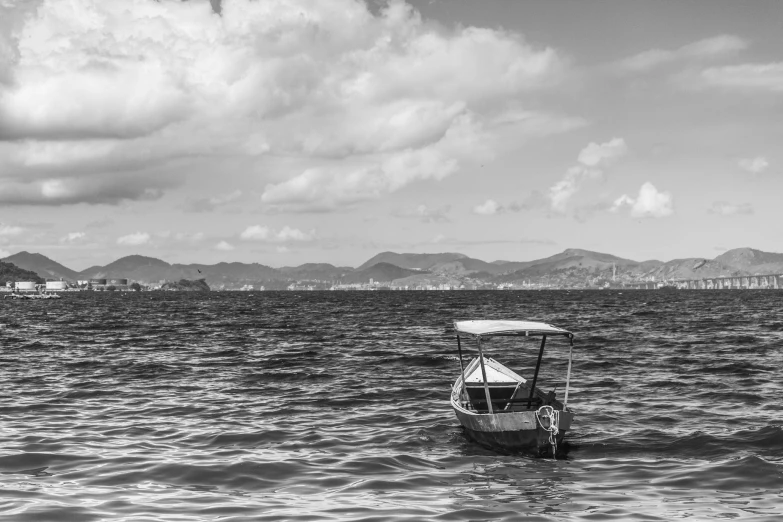 a small boat sailing in the ocean under a cloudy sky