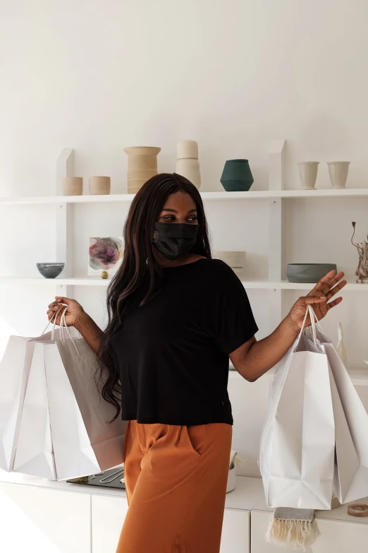 a woman wearing a face mask holding two shopping bags