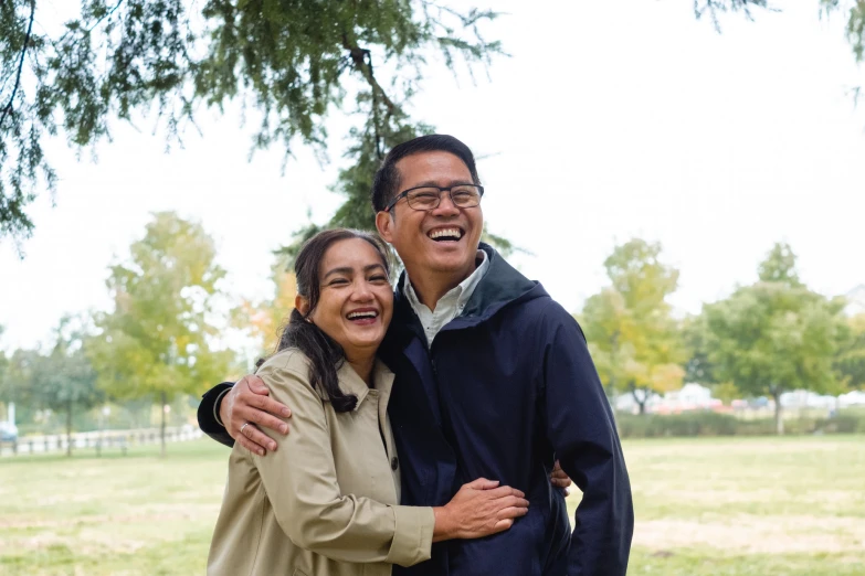 an old man and woman standing in front of a tree