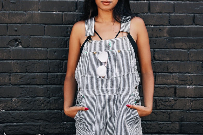 a woman is standing by the brick wall