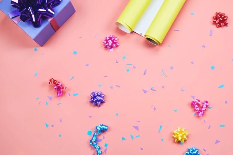 a box with confetti sits on a pink background surrounded by confetti sprinkles