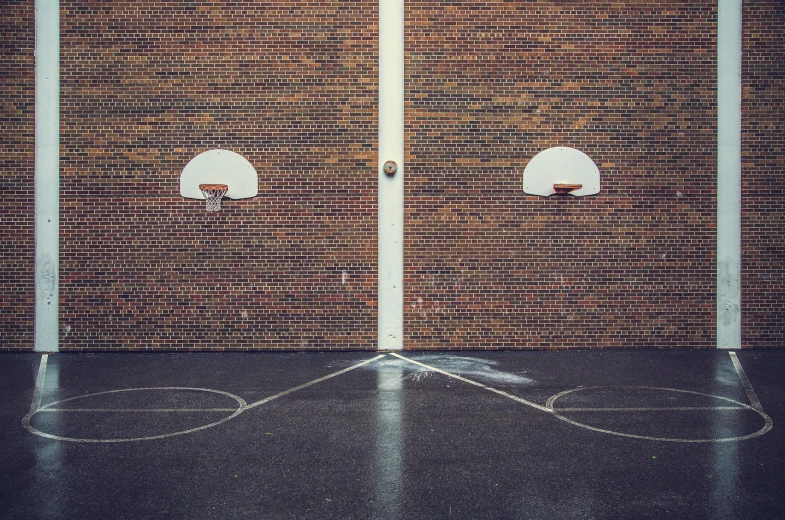 two basketballs on the floor in front of a brick wall