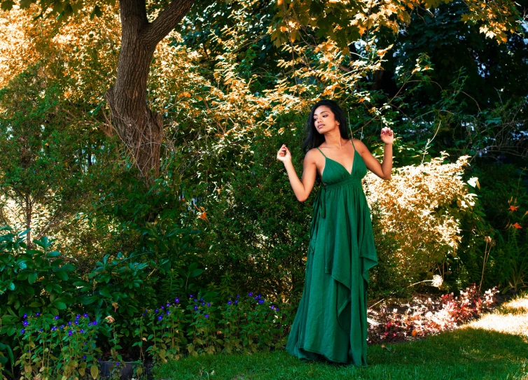 a beautiful woman in a dress standing under a tree