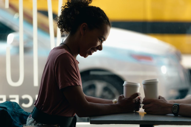 a woman sitting at a table next to two coffee cups