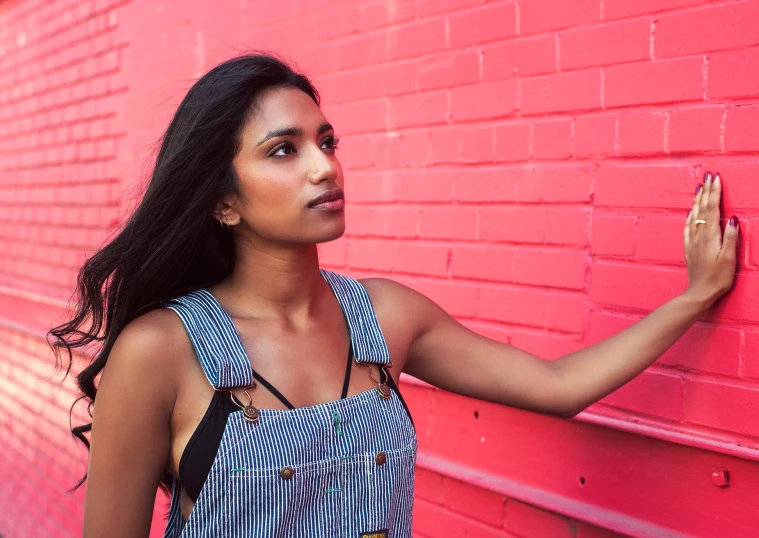 the young woman is standing near a brick wall