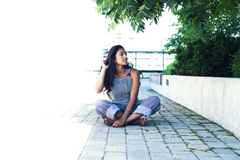 a woman sitting on a brick floor in the shade