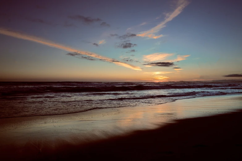 a sunset over the ocean on a beach