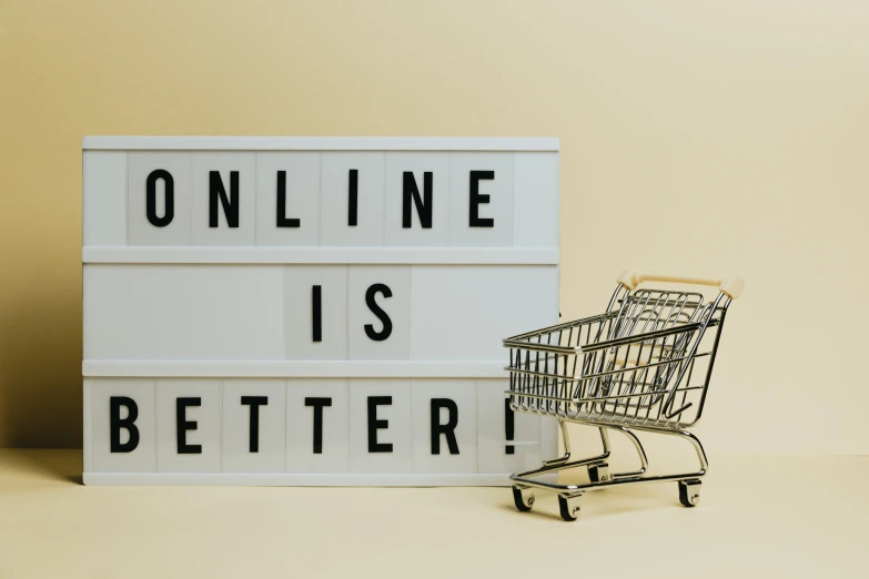 a mini shopping cart next to an online is better sign