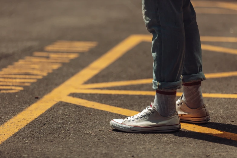 a person standing in the street wearing white tennis shoes