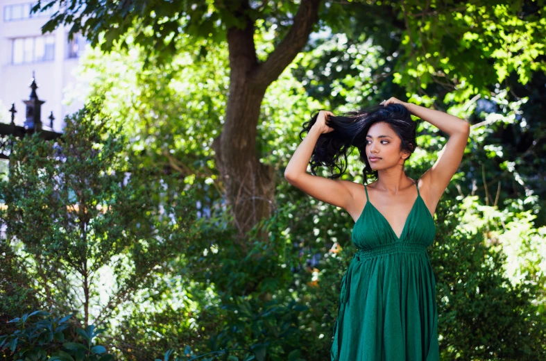 woman in green dress posing at trees and bushes